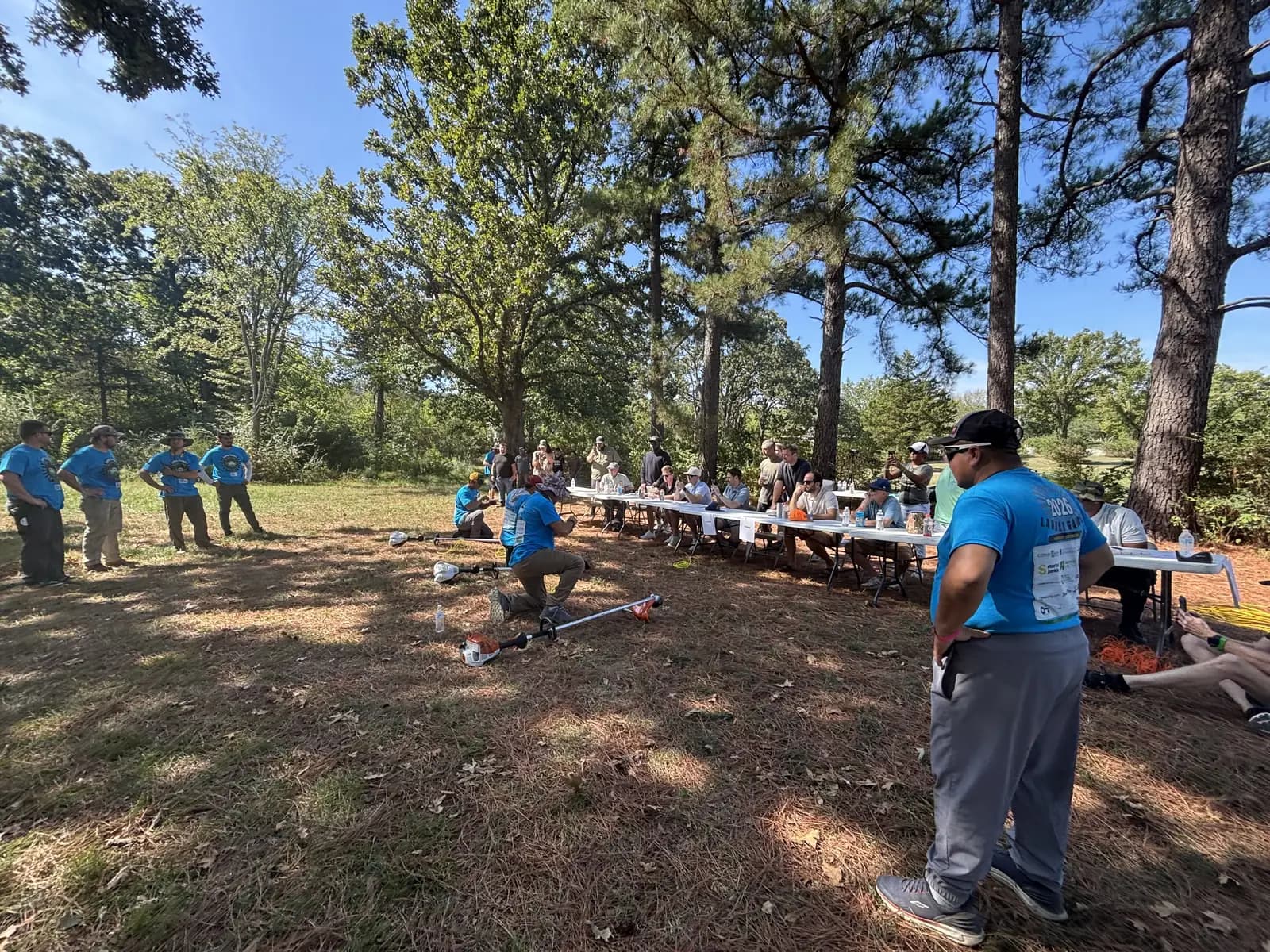 Competitors restring trimmers in front of a full judges’ table and spectators at the 2026 Lawnly Games